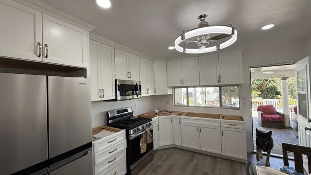 White shaker cabinets, stainless appliances and a fan light installed